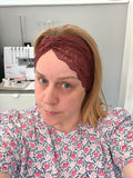 Person wearing a red headband in front of a sewing machine