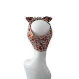 A multicolor patterned headband with cat ears, displayed on a white mannequin head against a plain white background.
