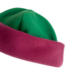 A close-up of a soft fleece hat with a bright green crown and a magenta-pink brim, shown on a plain white background.