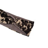 A close-up of a fabric headband with a black, beige, and brown abstract splatter pattern, featuring a solid gray elastic band.