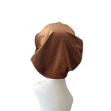 Brown beret on a mannequin head against a white background