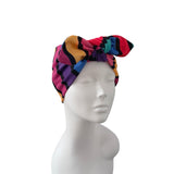 A multicolor patterned headwrap turban hat displayed on a white mannequin head against a plain white background.