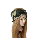 A camouflage-patterned twisted headband displayed on a mannequin head with long light brown hair, set against a plain white background.