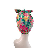 A floral fabric headwrap or turban hat displayed on a white mannequin head against a plain white background.