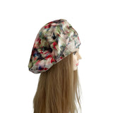 Multicolored satin headscarf on a mannequin head with long hair against a white background