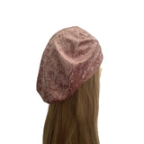Pink velvet beret on a mannequin head with long hair against a white background