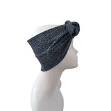 A dark blue and black leopard print headband with a large side knot, displayed on a white mannequin head in profile against a white background.
