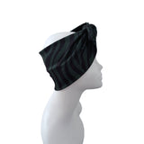 A dark green and black zebra-striped headband with a side knot, displayed on a white mannequin head in profile against a white background.