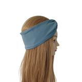 A dusty blue fabric headband with a side knot detail, shown on a mannequin head with long light brown hair against a plain white background.