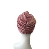 Pink velvet turban on a white mannequin head against a white background