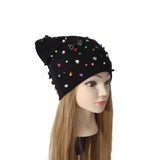 A black slouchy beanie hat embellished with colorful rhinestones and beads, displayed on a mannequin head with long blonde hair against a plain white background.