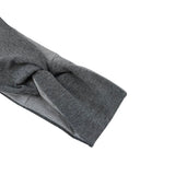 A close-up of a dark gray heathered knit fabric, likely a sleeve cuff or scarf, folded to show its texture and stitching against a plain white background.