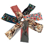 Six women's knit headbands arranged in a circular fan pattern on a solid white background, showcasing various colors and patterns including florals, botanical, and solid tones.