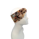A patterned fabric headband in earthy brown, beige, and black tones, shown wrapped around a white mannequin head in profile against a plain white background.
