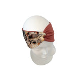 A fabric headband with a solid rust-brown side and an all-over floral print center, displayed on a white mannequin head against a white background.