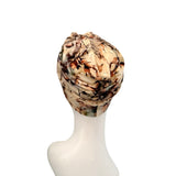 A patterned headwrap turban hat displayed on a white mannequin head against a plain white background.