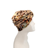 A multicolor abstract patterned headwrap turban cap displayed on a white mannequin head in profile against a solid white background.