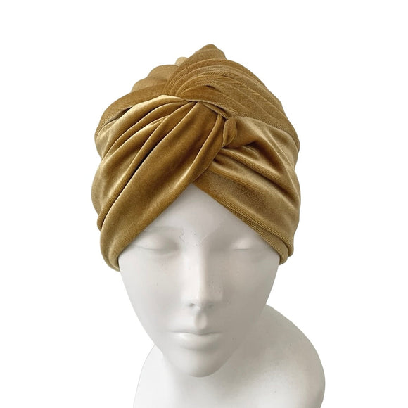 gold turban on a mannequin head against a white background