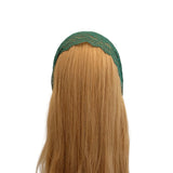 Green headband on a mannequin head with long blonde hair against a white background
