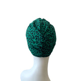 Green leopard print headscarf on a white mannequin head against a white background