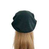 Dark green beret on a mannequin head with blonde hair against a white background