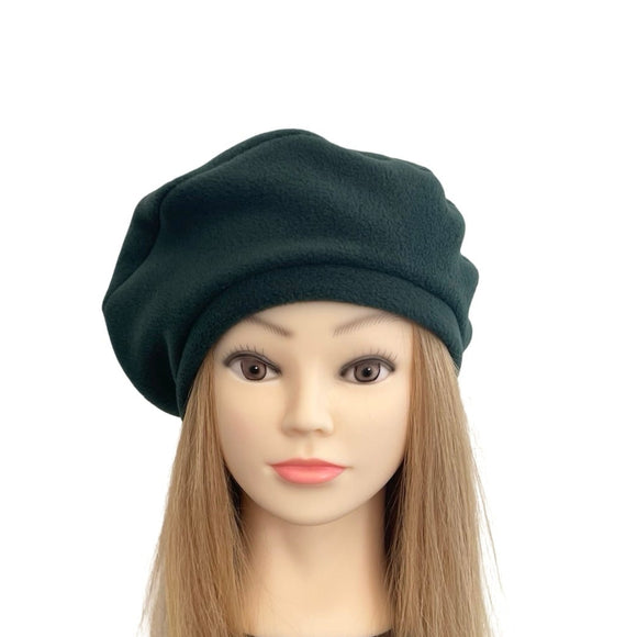 Mannequin head with long blonde hair wearing a green beret on a white background