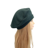 Dark green beret on a mannequin head against a white background