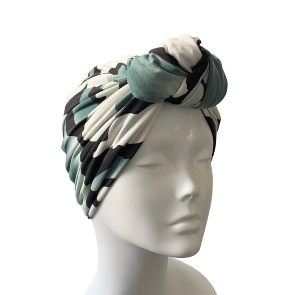 Turban with black, white, and green pattern on a mannequin head against a white background