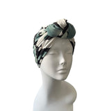 Turban with black, white, and green pattern on a mannequin head against a white background