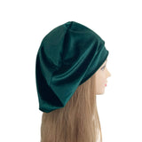 Mannequin head wearing a green velvet headscarf on a white background