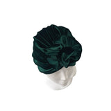 Dark green velvet turban on a mannequin head against a white background