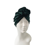 Dark green turban on a mannequin head against a white background