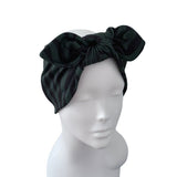 A black satin bow headwrap turban hat displayed on a white mannequin head against a plain white background.