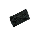 A dark green and black striped fabric headband with a large twisted knot at the center, shown on a plain white background.