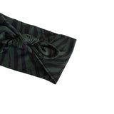 A dark green and black zebra-striped fabric headband with a knotted bow detail, shown on a plain white background.