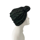 Green patterned turban on a mannequin head against a white background