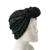 Green and black patterned headscarf on a mannequin head against a white background