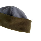 Close-up of a soft fleece beanie hat showing the outer gray-blue panel and the folded olive-brown inner panel on a plain white background.