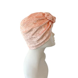 Pink velvet turban on a mannequin head against a white background