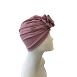 Mauve headscarf with a flower on a mannequin head against a white background