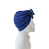 Blue turban with decorative bow on a mannequin head against a white background