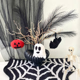 Halloween-themed decorations including a ghost, pumpkin, and skeleton on a black and white patterned tablecloth.