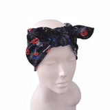 A black fabric headband with a Halloween-themed print of orange pumpkins, red flowers, and spiderwebs, styled on a white mannequin head against a white background.