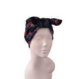 A black headwrap turban hat with a red and blue floral pattern, displayed on a light gray mannequin head against a white background.