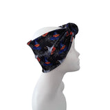 A black twisted headband with a Halloween spiderweb and spider print, displayed on a white mannequin head in profile against a white background.