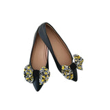 Black flats with floral embellishments on a white background