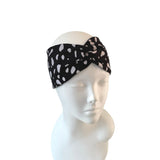 Black headband with white polka dots on a mannequin head against a white background