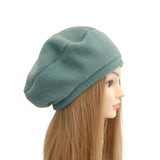 Green beanie on a mannequin head with long hair against a white background
