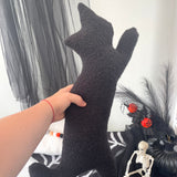 Person holding a pair of black textured socks with Halloween decorations in the background.