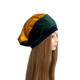 Mannequin head wearing a gold and green headscarf on a white background